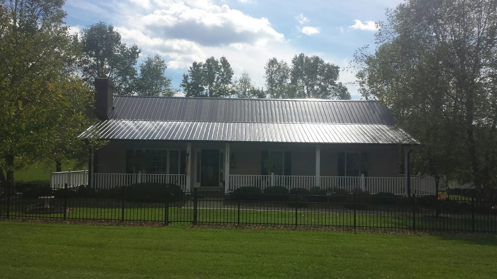 Gray metal roof on a brick ranch with a full width front porch — Gutter Guard Installation work by our crew in Creighton